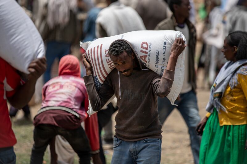An Ethiopian man carries a sack of wheat on his shoulders to be distributed by the Relief Society of Tigray in the town of Agula, in northern Ethiopia in 2021.