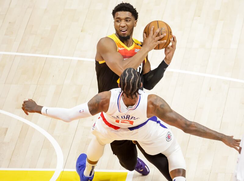 LA Clippers guard Paul George is charged with a foul as Jazz guard Donovan Mitchell drives during Game 1 in Salt Lake City.