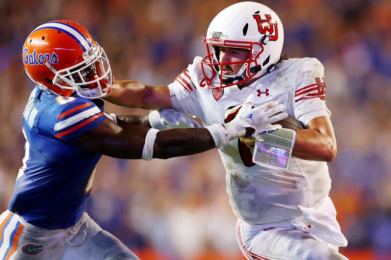 Utah Utes quarterback Cameron Rising stiff-arms Florida Gators safety Trey Dean III.