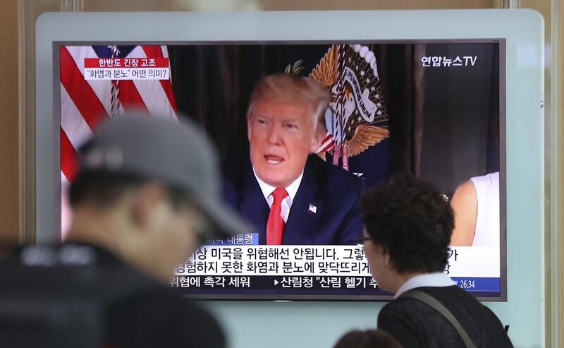 People walk by a TV screen showing a local news program reporting with an image of U.S. President Donald Trump at the Seoul Train Station in Seoul, South Korea, Wednesday, Aug. 9, 2017. North Korea and the United States traded escalating threats, with Pre
