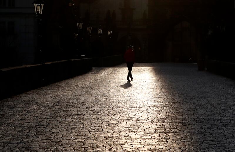 A man walks across an empty Charles Bridge in Prague, Czech Republic, Monday, March 16, 2020. The Czech government has imposed further dramatic restrictions on the movement in efforts to contain the outbreak of the coronavirus.