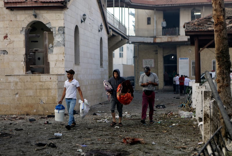 Palestinians carry belongings as they leave al-Ahli hospital, which they were using as a shelter, in Gaza City on Oct. 18, 2023.