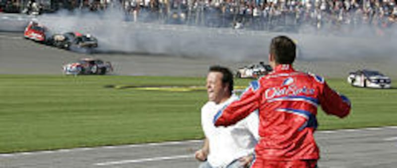 Members of Tony Stewart's pit crew react to his win as a group of cars spin on the tri-oval at the end of the Hershey's Kissables 300 NASCAR Busch race at Daytona International Speedway on Saturday.