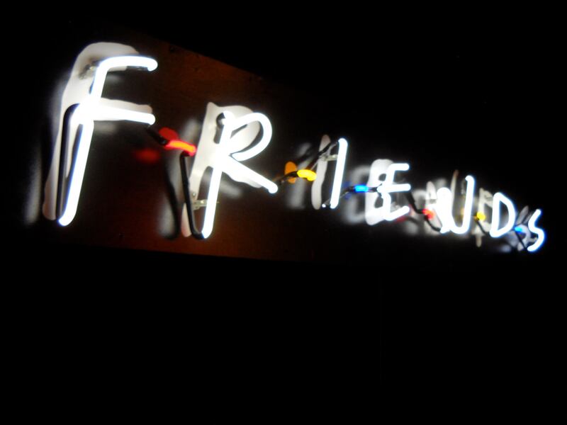 A neon sign glows in the night, showing the “Friends” sitcom logo.
