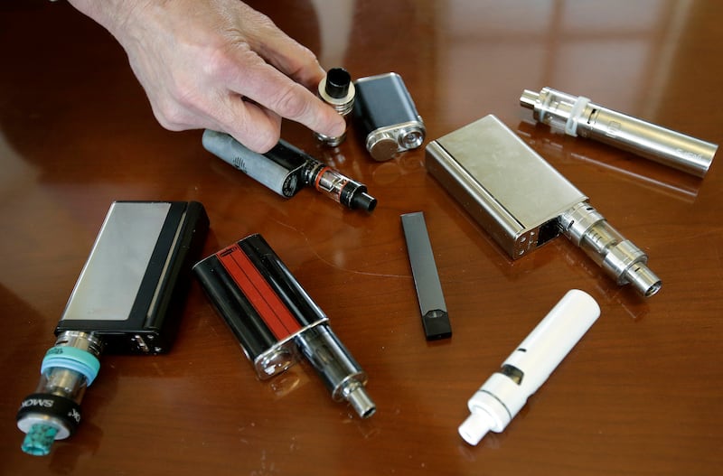 In this Tuesday, April 10, 2018, file photo, a high school principal displays vaping devices that were confiscated from students in such places as restrooms or hallways at the school in Massachusetts. The Food and Drug Administration is planning on requir