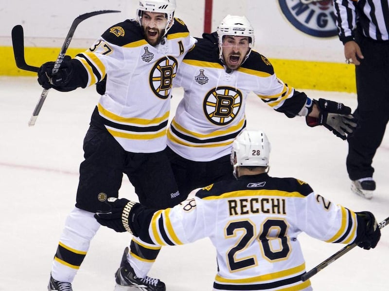 Boston Bruins center Patrice Bergeron , left, celebrates with teammates Brad Marchand and Mark Recchi after scoring against the Vancouver Canucks during the first period of Game 7 of the NHL hockey Stanley Cup Finals on Wednesday, June 15, 2011, in Vancou