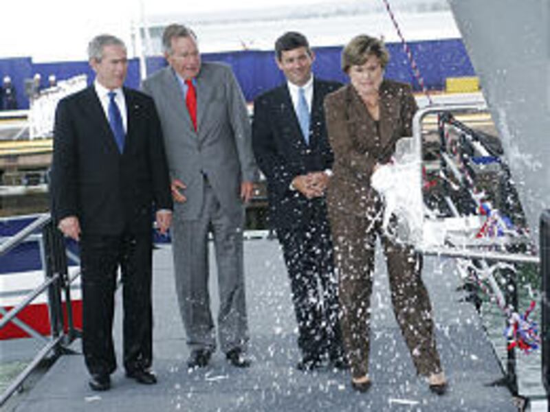 Doro Bush Koch christens the carrier as President Bush and his father watch.