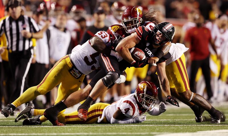 Utah tight end Dalton Kincaid is brought down by USC linebackers Shane Lee (53) and Tuasivi Nomura at Rice-Eccles Stadium.