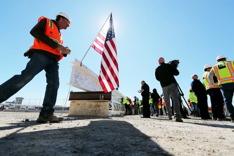 Workers sign the final beam to be placed on the north concourse at the Salt Lake City International Airport is pictured with an American flag during a topping-off ceremony on Tuesday, March 19, 2019. The airport is currently undergoing a $3.6 billion airp