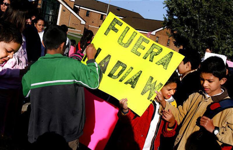 Students and their parents rally for the resignations of the director and business manager of the Dual Immersion Academy in Salt Lake City on Friday.