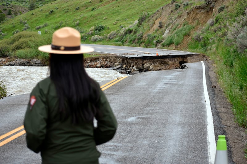 A Yellowstone National Park ranger is seen standing near a road wiped out by flooding along the Gardner River the week before.