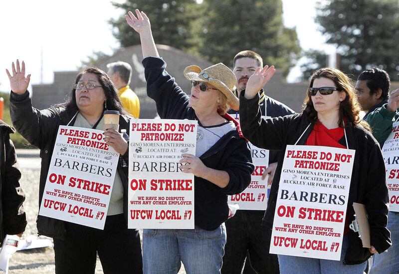 Striking barbers wave at motorist as they picket at the main entrance to Buckley Air Force Base in Aurora, Colo., on Thursday, March 22, 2012.