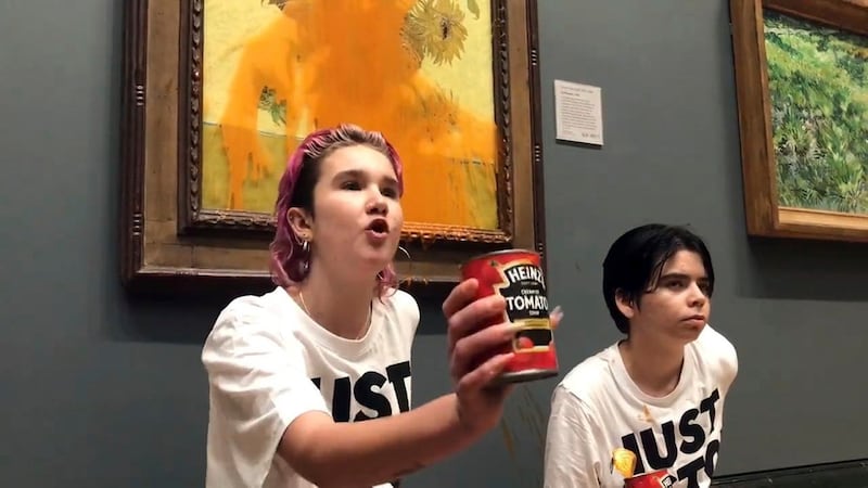 Handout photo of two protesters who have thrown tinned soup at Vincent Van Gogh’s famous 1888 work “Sunflowers” in London.