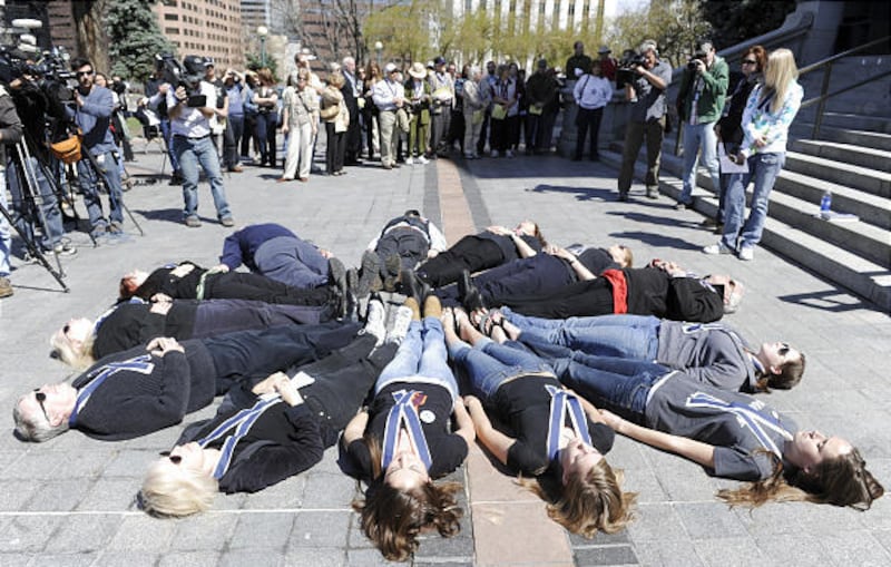 Thirteen people lay down to symbolize those killed in the Columbine school shooting at a Columbine Remembrance and Rededication on the 10th anniversary of the Columbine attack, at the Capitol in Denver, on Monday.