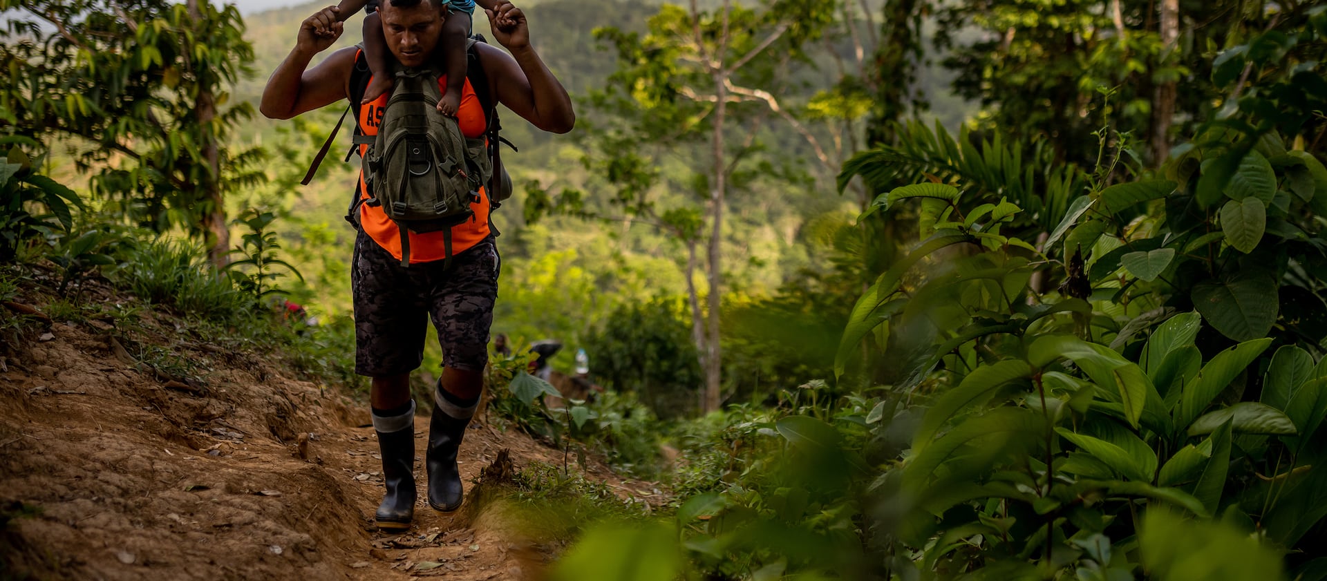 A guide carries the child of Haitian migrants through the Darién Gap