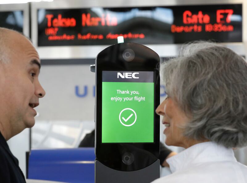 U.S. Customs and Border Protection officer Sanan Jackson, left, helps a passenger navigate one of the new facial recognition kiosks at a United Airlines gate before boarding a flight to Tokyo, Wednesday, July 12, 2017, at George Bush Intercontinental Airp