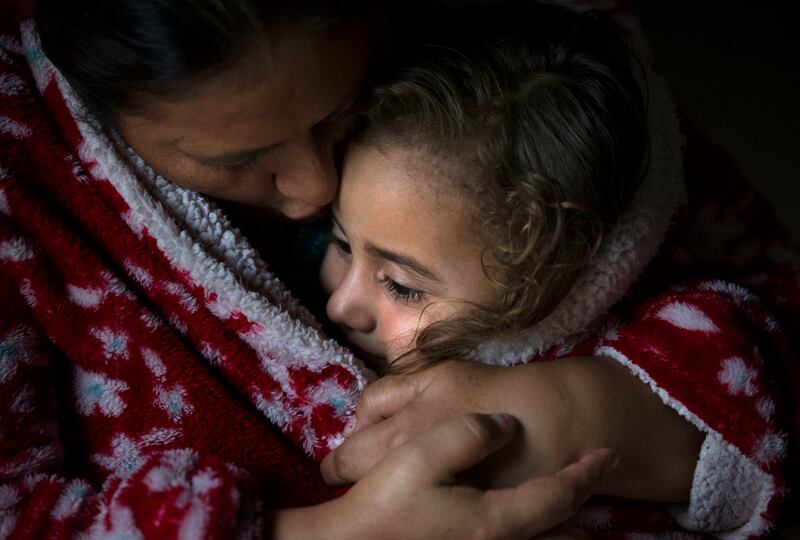 Maria and her youngest daughter, Nathalie, cuddle during a downpour in Jerez, Guatemala, on Tuesday, Oct. 16, 2018.