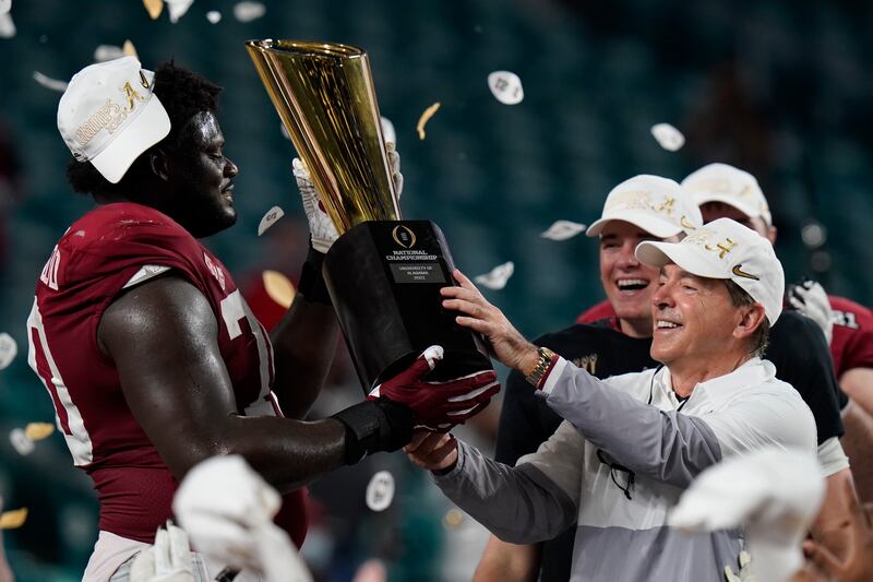 Alabama head coach Nick Saban and offensive lineman Alex Leatherwood hold the College Football Playoff championship trophy.