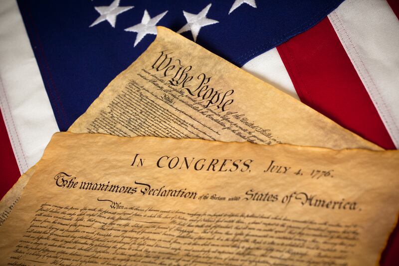 the United States Constitution and Declaration of Independence on a Betsy Ross Flag background