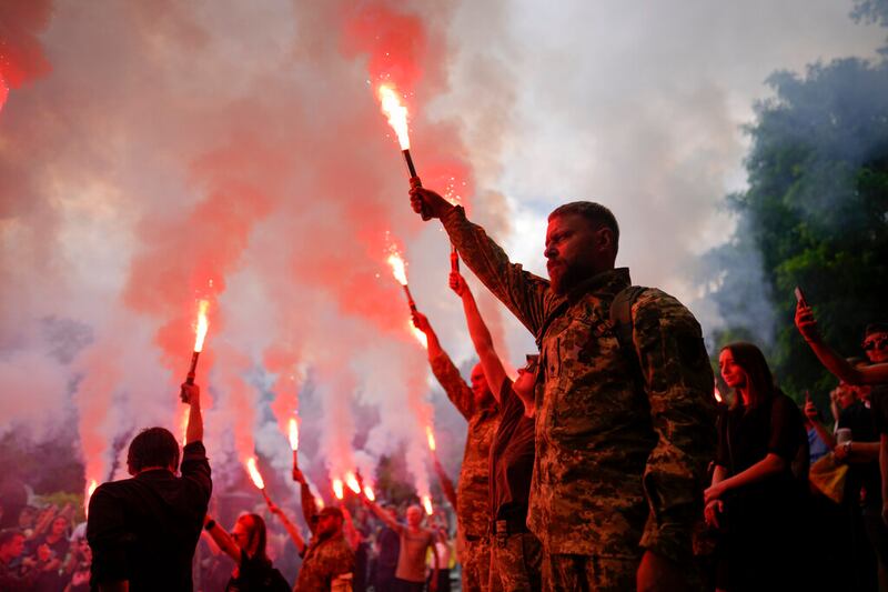 Soldiers hold flares as they attend the funeral.