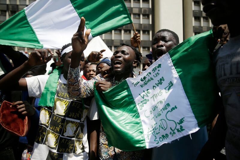 People hold banners as they demonstrate on the street to protest against police brutality, in Lagos, Nigeria, Tuesday Oct. 20, 2020. After 13 days of protests against police brutality, authorities have imposed a 24-hour curfew in Lagos, Nigeria’s largest city as moves are made to stop growing violence.