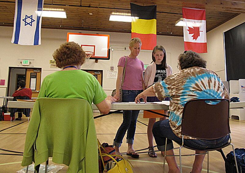 Amy O'Brien, standing at center left, accompanied by her daughter, Ruby Stigers, standing at right, selects a primary election ballot at Lowell Elementary School in Boise, Idaho on Tuesday, May 15, 2012. Tuesday's election marked the first time that Idaho