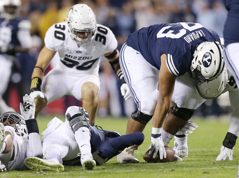 BYU offensive lineman Ului Lapuaho, right, tries to recover a Tanner Mangum fumble as BYU and Missouri play at Arrowhead Stadium in Kansas City Missouri Saturday, Nov. 14, 2015.