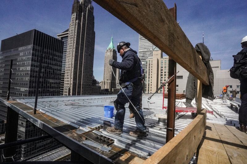 Construction workers install roofing on a high-rise in Manhattan’s financial district in New York.