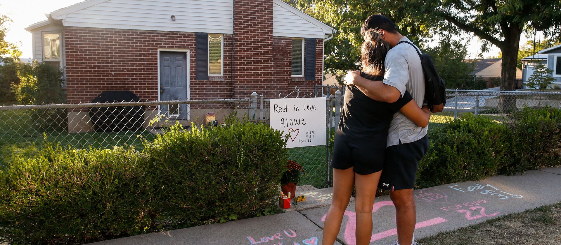Samuelu Elisaia and Madison Jacobus embrace each other in front of a makeshift memorial for Aaron Lowe.