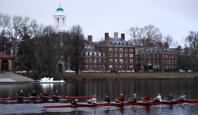 FILE - In this March 7, 2017 file photograph, rowers pass the campus of Harvard University as they paddle down the Charles River in Cambridge, Mass. Harvard and the group Students for Fair Admissions will file dueling analyses of the Ivy League school's a