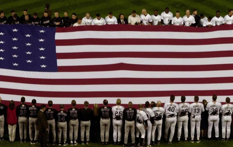 FILE - In this Monday, Sept. 17, 2001 file picture, members of the Colorado Rockies and Arizona Diamondbacks meet in the center of the infield to hold the American flag during the singing of "God Bless America" and the national anthem to mark the first ba