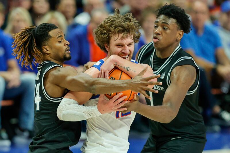 Boise State guard Max Rice (12) battles against the defense of Utah State guard Josh Uduje (14) and forward Great Osobor.