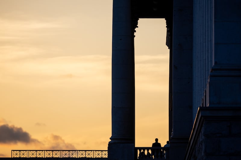 People are silhouetted against the sunset on the steps of the Capitol in Salt Lake City.