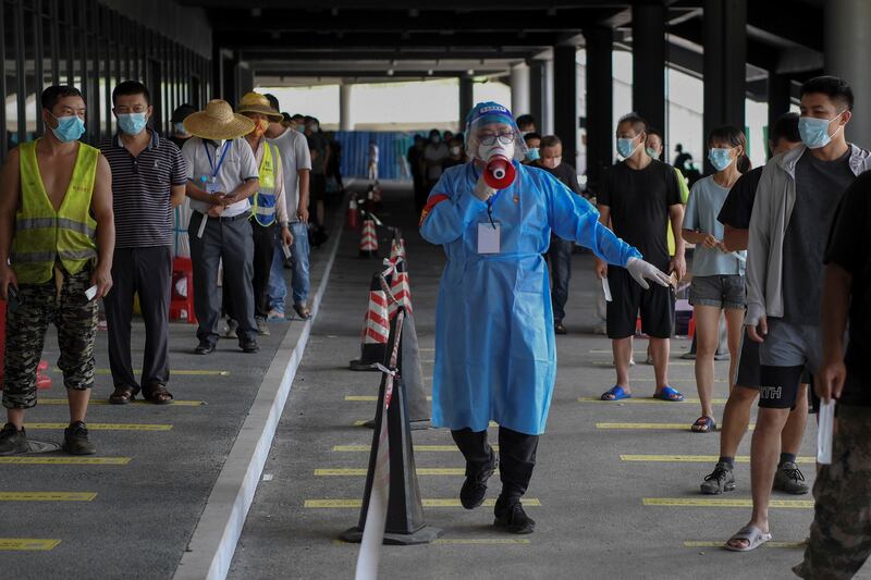 A volunteer uses a loud speaker to advise people to keep social distancing at a COVID-19 testing site in China.