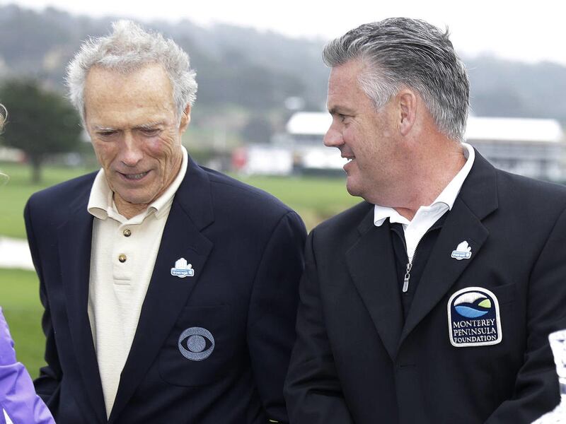 Steve John, right, tournament director and CEO of the Monterey Peninsula Foundation, talks with actor and director Clint Eastwood, left, on the 18th green of the Pebble Beach Golf Links during the awards ceremony for the AT&T Pebble Beach Pro-Am golf tour