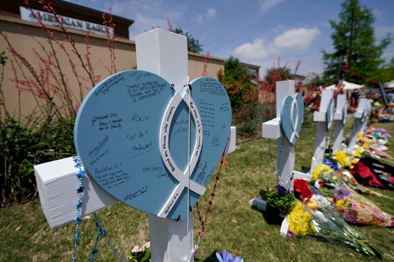 A cross with a name on it, and notes left by visitors, stands by others at a makeshift memorial by the mall where several people were killed in Saturday’s mass shooting, Monday, May 8, 2023, in Allen, Texas.