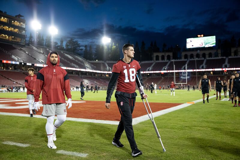 Stanford Cardinal quarterback Tanner McKee (18) uses a crutch on the field.
