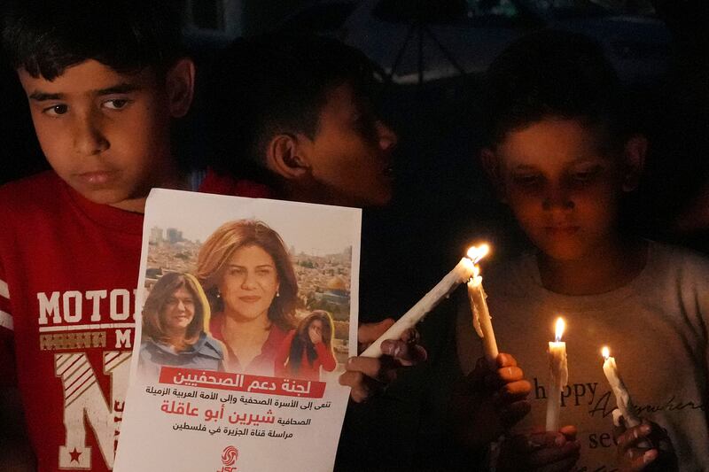 Palestinian children carry light candles and pictures of slain Al Jazeera journalist Shireen Abu Akleh.