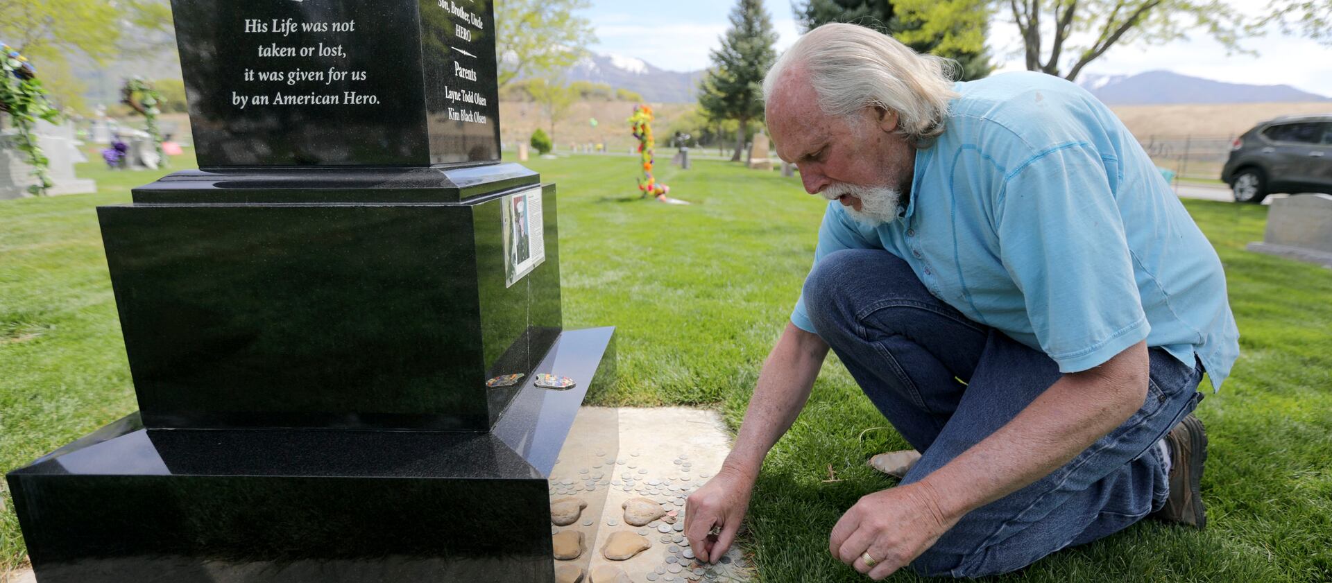 Layne Olsen looks at coins left at the Salem, Utah, grave of his son, Lance Cpl. Nigel Olsen, who was killed in action in Afghanistan.