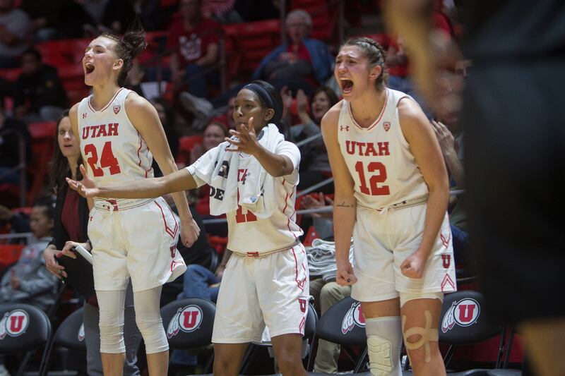 Utah Utes wing Tilar Clark (24), guard Erika Bean (11) and forward Emily Potter (12) cheer during the Utes' 81-46 victory over the Washington Huskies at the Huntsman Center in Salt Lake City on Sunday, Feb. 18, 2018.