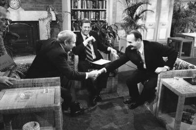 G. Gordon Liddy, right, of Watergate fame, leans over to shake with columnist Jack Anderson on national television as host David Hartman of “Good Morning America,” center, watches, April 17, 1980.