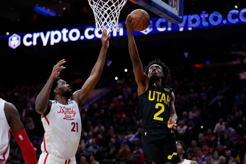 Utah Jazz’s Collin Sexton, right, goes up for a shot against Philadelphia 76ers’ Joel Embiid during the second half of an NBA basketball game, Sunday, Nov. 13, 2022, in Philadelphia.