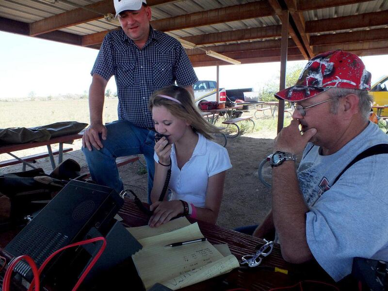 Fourteen-year-old Samantha Bruton makes her first contact through a ham radio at the Lea County Amateur Radio Club field day on Saturday, June 23, 2012 at Camp Jim Murray near the Hobbs County Club.Her father, Bobby Bruton, left and Lea County Amateur Rad