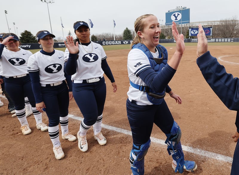 BYU Cougars catcher Hailey Morrow (20) high-fives a coach prior to a game with Boise State in Provo, March 21, 2023.