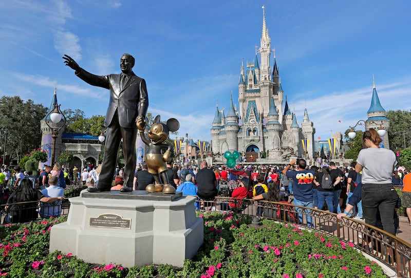 In this Wednesday, Jan. 9, 2019 photo, guests watch a show near a statue of Walt Disney and Micky Mouse in front of the Cinderella Castle at the Magic Kingdom at Walt Disney World in Lake Buena Vista, Fla.