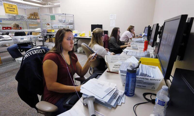 Workers verify ballots at the Salt Lake County Election Division in Salt Lake City, Monday, Aug. 10, 2015. At front is Ashley Lee.