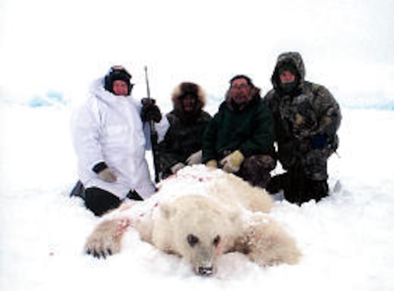 Hunter Jim Martell, left, and guide Roger Kuptana, center right, pose with a hybrid bear shot during a hunting expedition on Banks Island, Northwest Territory, Canada.