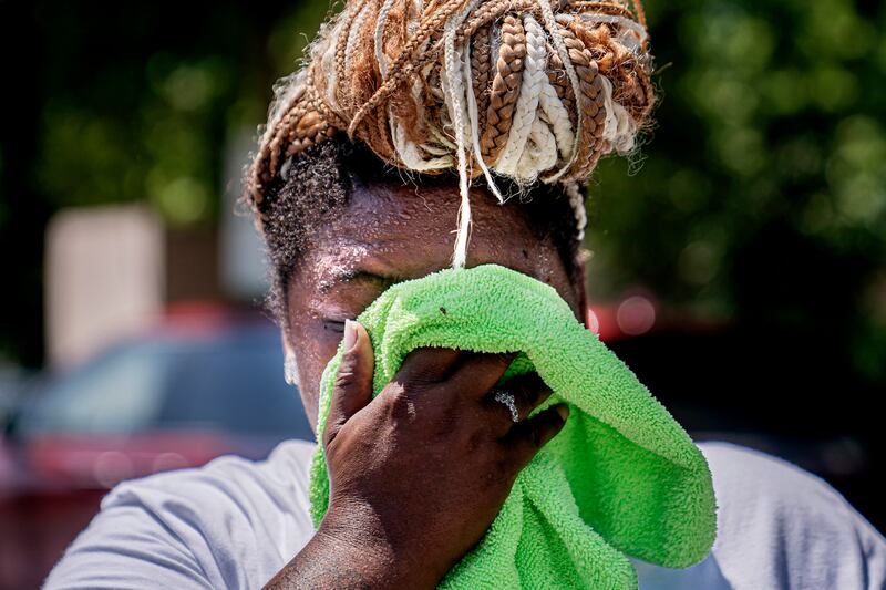 Nicole Brown wipes sweat from her face while setting up a beverage stand in Washington on Friday, July 22, 2022.