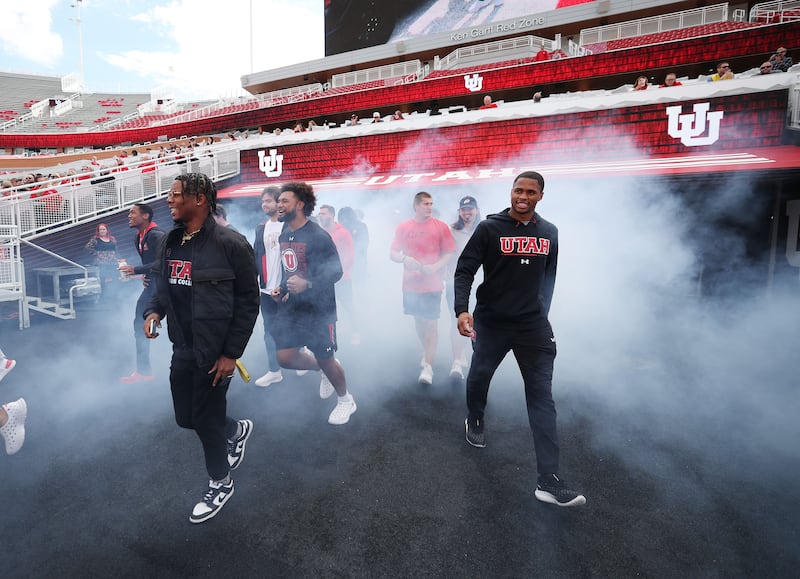 Utah football players walk onto the field to celebrate getting a Dodge truck given to them by the Crimson Collective.