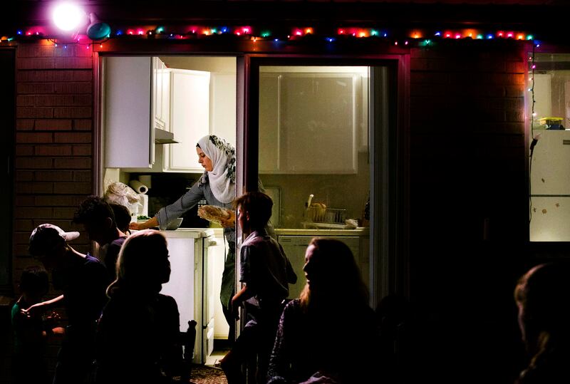 Baraa Huraideen cleans up as the Hredeen family, the Hamad family and volunteers with Catholic Community Services gather outside to chat after sharing iftar at the Hredeen home in Millcreek on Tuesday, June 6, 2017.